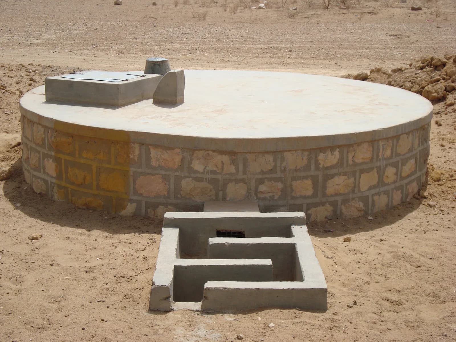 A covered traditional rainwater harvesting tank with an inlet channel in Rajasthan, India